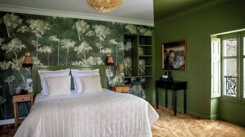 A bedroom with a large bed, green walls, a window with a view, and a painting on the wall.