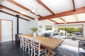Un intérieur moderne avec une table à manger en bois, des chaises blanches, un canapé et une cheminée.