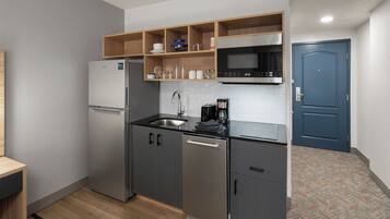 Una cocina compacta con refrigerador, microondas, pileta y horno empotrado.