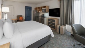Hotellihuone, jossa on suuri sänky, työpöytä, tuoli, televisio, mikroaaltouuni ja jääkaappi.