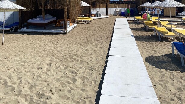A beach with thatched umbrellas, sun loungers, and a white pathway. - Moj Dom Küçükköy (Ayvalik)