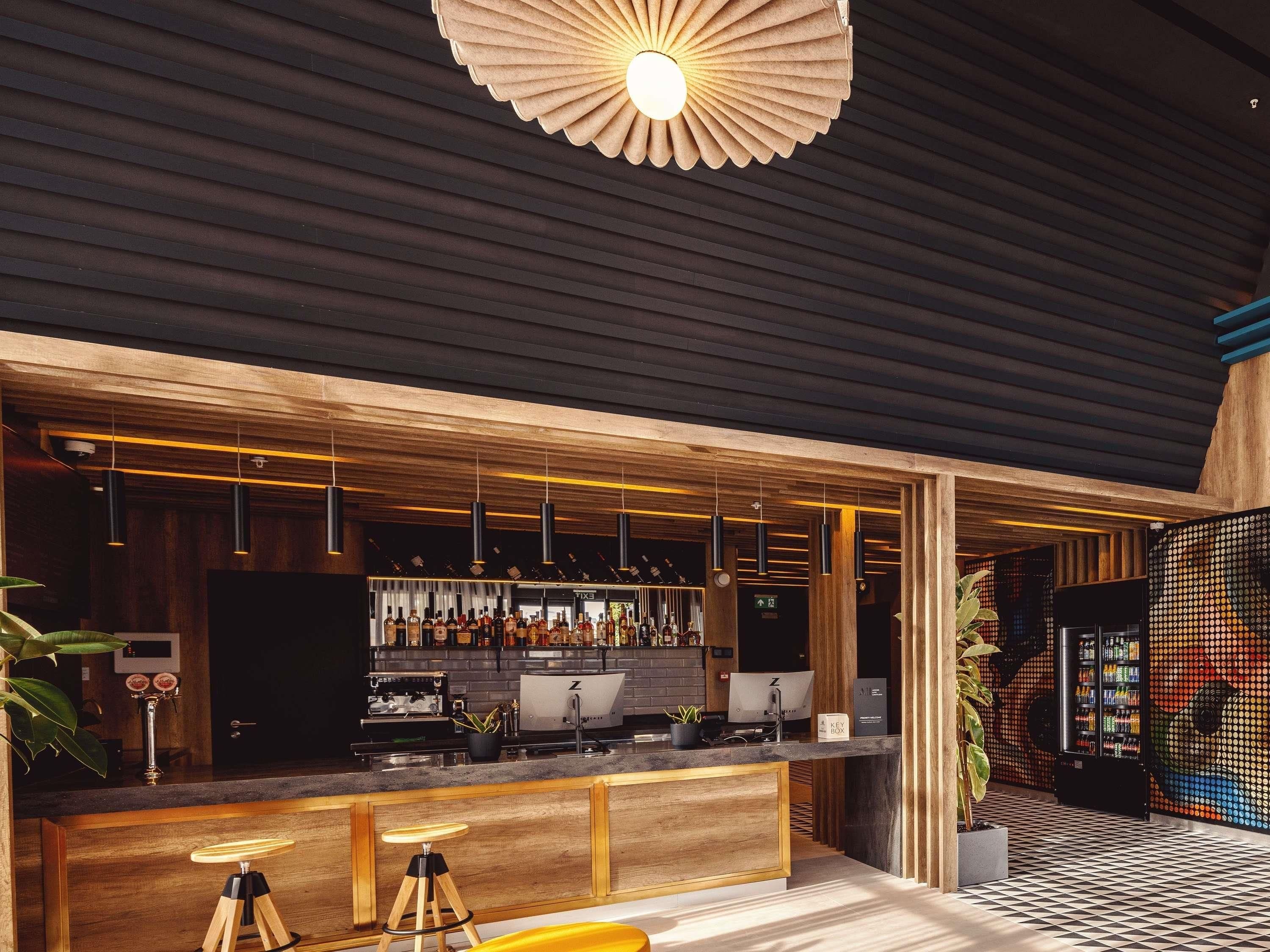 Una zona de bar con mostrador de madera, lámparas colgantes y un ventilador de techo.