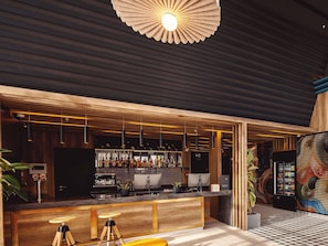 A bar area with a wooden counter, hanging pendant lights, and a ceiling fan. - Ibis Tbilisi City (Tbilisi)