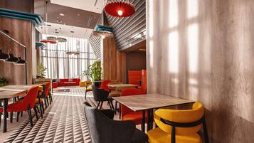 A modern interior with tables and chairs, a patterned floor, and a large window allowing natural light.