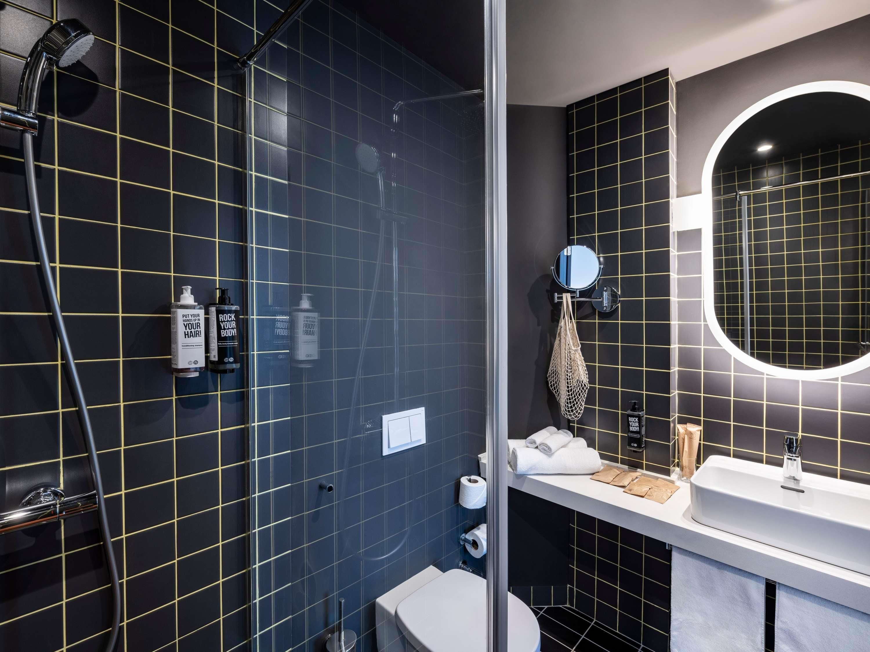 Une salle de bain moderne avec une douche à parois de verre, un lavabo blanc et un miroir doté d’un cadre rond.