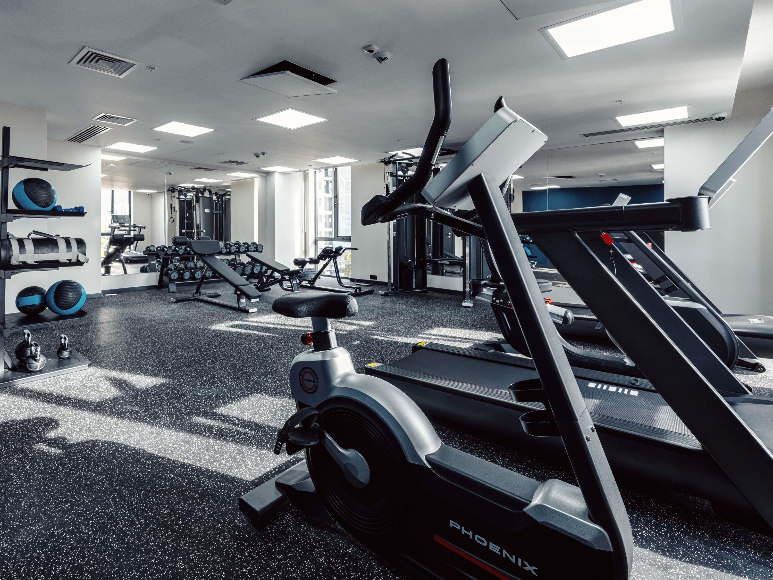Une salle de sport équipée de matériel d’exercice, notamment des tapis de course et des poids.