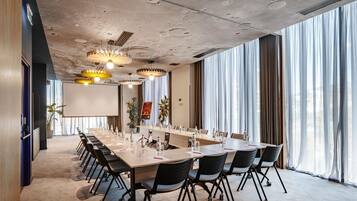 A conference room with a long table, chairs, and a projector screen.