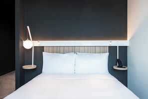 A modern hotel room with a large bed, bedside tables, and a wall-mounted light fixture. - Ibis Tbilisi City (Tbilisi)
