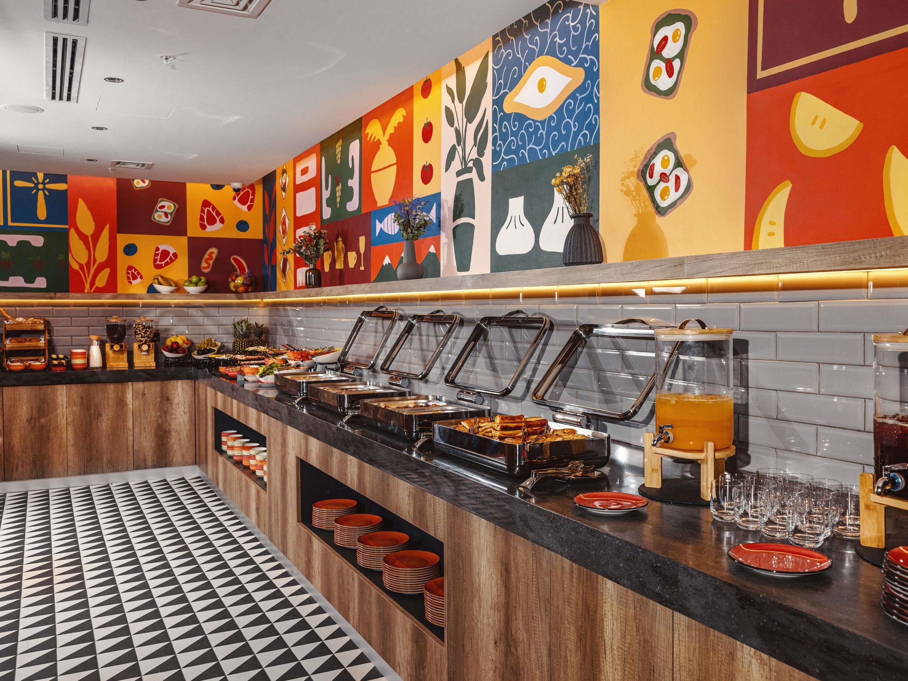 A buffet area with various food stations, a tiled floor, and colorful wall art.
