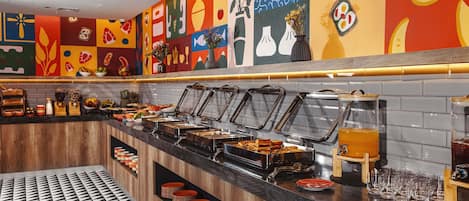 A buffet area with various food stations, a tiled floor, and colorful wall art.