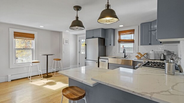 A modern kitchen with a marble countertop, two pendant lights, and a built-in stove. - Renovated Water Haus ⎥ +8 beds ⎥ Historic Waterfront

 (Warren)
