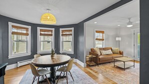 A modern living room with a round dining table, a sofa, and a chandelier. - Renovated Water Haus ⎥ +8 beds ⎥ Historic Waterfront

 (Warren)