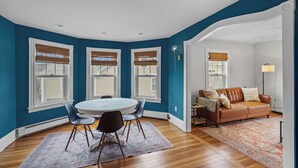 A room with a round table and chairs, a brown leather sofa, and a patterned rug. - Renovated Water Haus ⎥ +8 beds ⎥ Historic Waterfront

 (Warren)