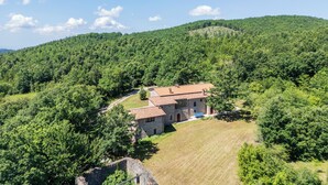 A stone house with a red roof surrounded by lush green hills. - Le Casaline Di Sopra Near Massa (Massa Marittima)