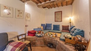 A cozy room with a wooden bench, a sofa, and a small table with plush toys. There are framed pictures on the wall and a candle on a table. - Le Casaline Di Sopra Near Massa (Massa Marittima)