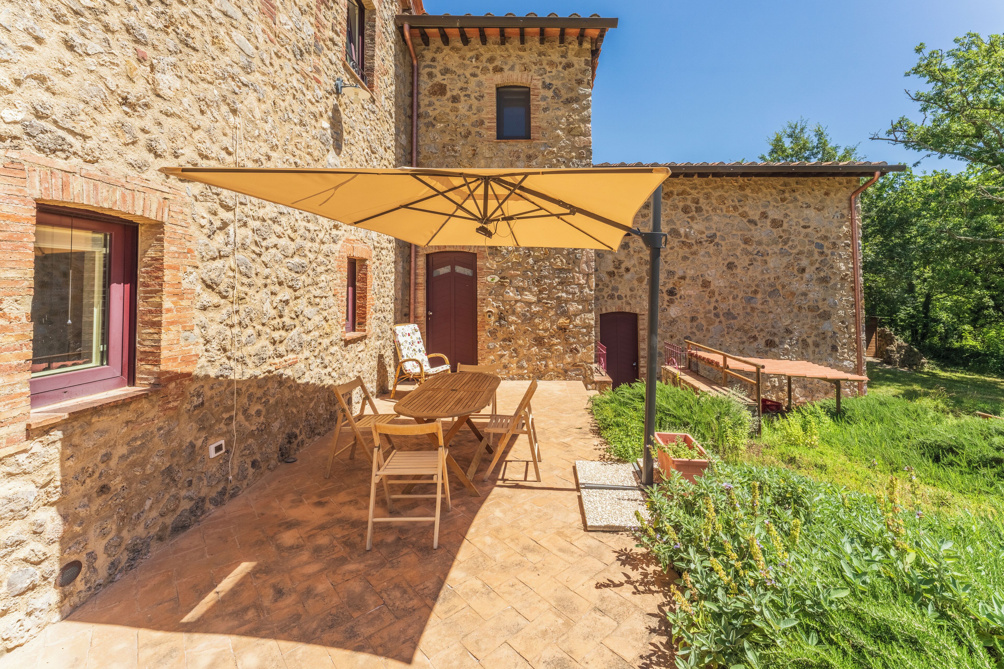 A stone building with a patio area featuring a table and chairs under a large umbrella.
