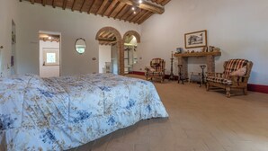 A spacious room with a large bed, wooden furniture, and a fireplace. - Le Casaline Di Sopra Near Massa (Massa Marittima)