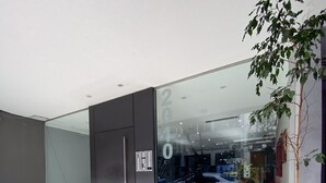 Une entrée moderne avec une porte en verre, un sol en métal ajouré et une plante en pot.