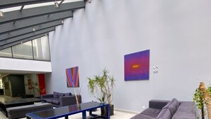 Un salon moderne avec un canapé d’angle, une table basse bleue et une grande fenêtre donnant sur un beau paysage.