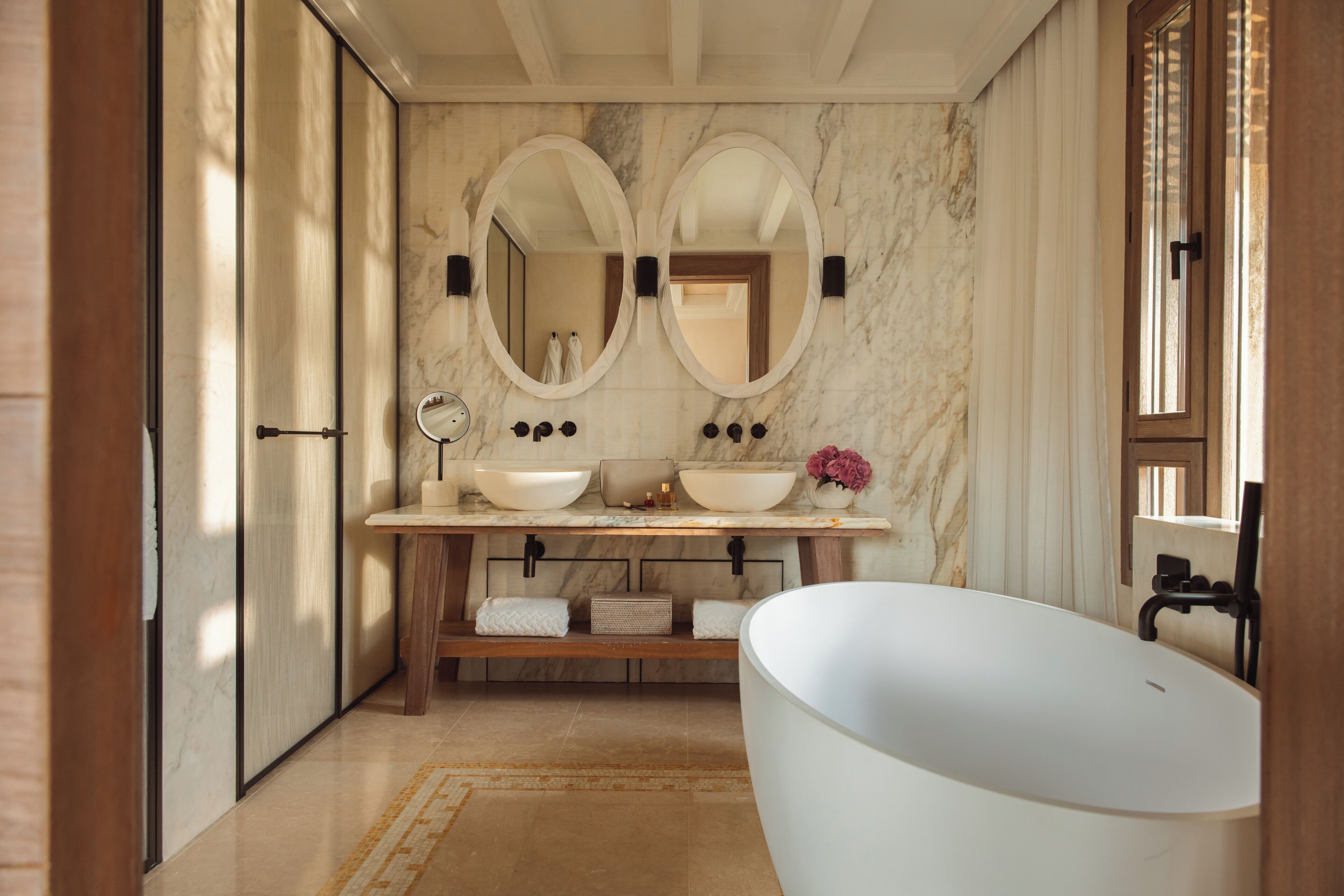 A modern bathroom with a freestanding bathtub, double sinks, and a large mirror above the vanity.