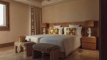 A spacious bedroom with a large bed, two bedside tables, a bench, and a window.