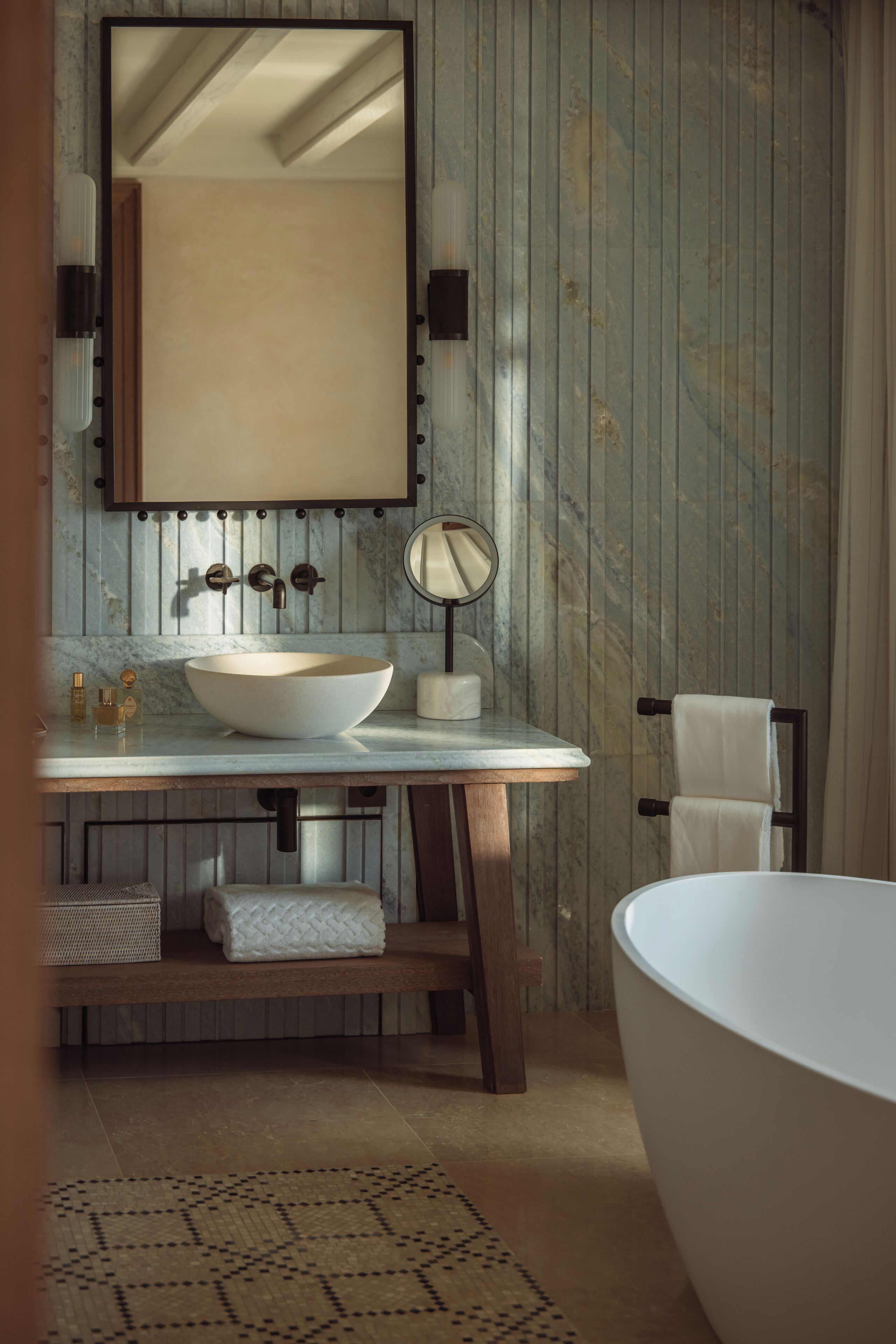 Une salle de bain avec un grand lavabo blanc, un miroir, un porte-serviettes et une baignoire sur pieds.