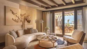 A modern living room with a curved sofa, a round coffee table, and a view of the outdoor patio. - Royal Mansour Tamuda Bay (M'diq)