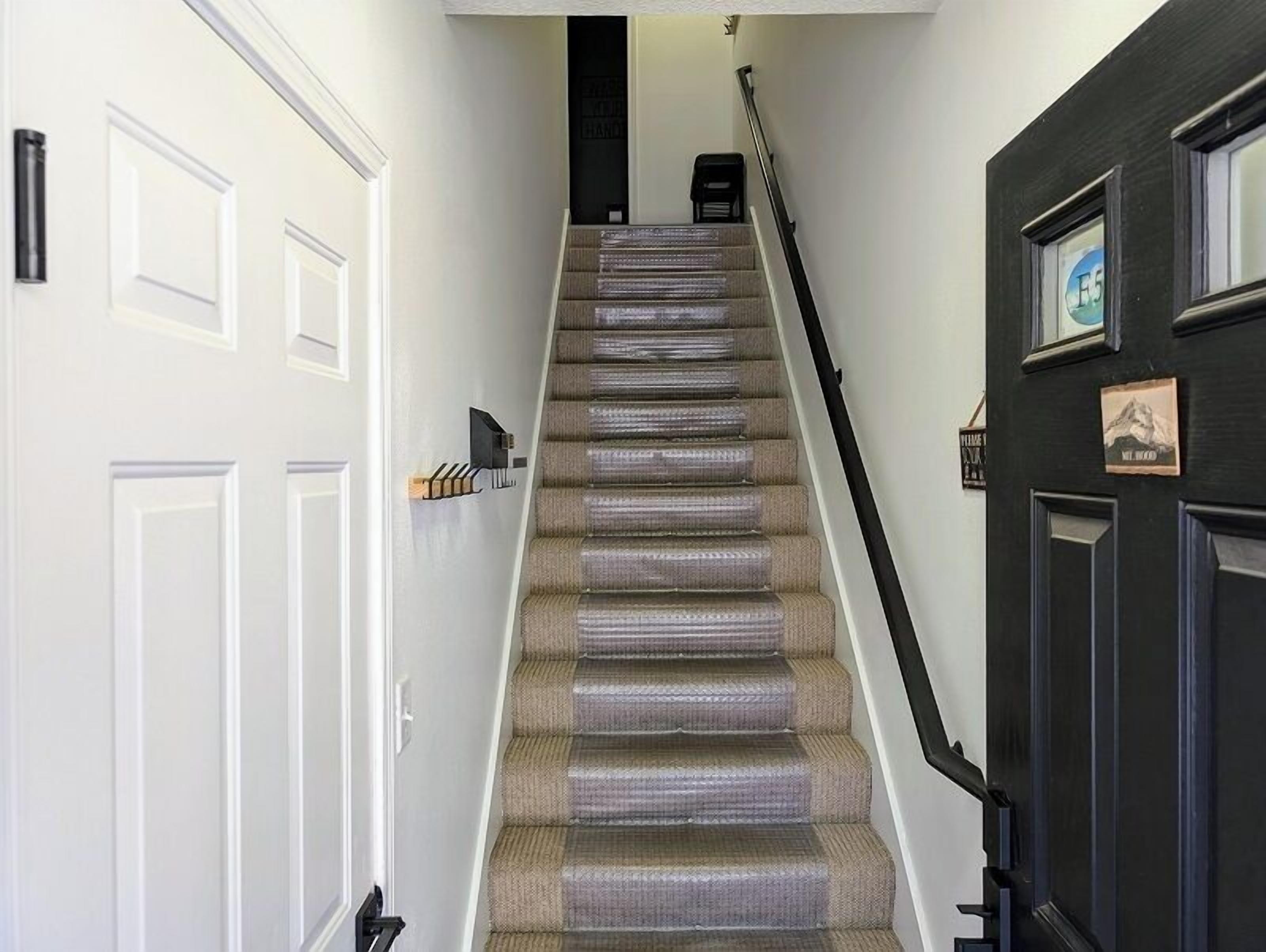 A staircase with carpeted steps, white doors, and a black door with a picture frame.