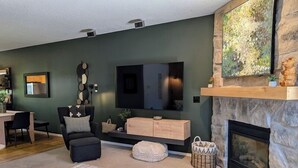 Una sala de estar moderna con chimenea de piedra, televisor de pantalla plana y comedor con mesa y sillas de madera.