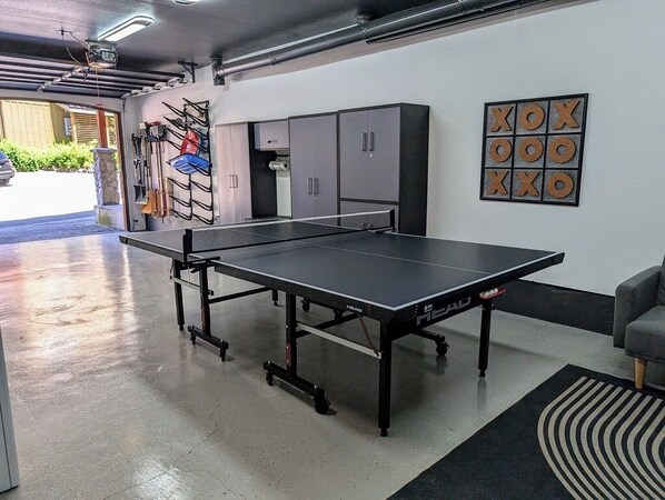 A ping pong table in a room with cabinets and a wall-mounted game board.