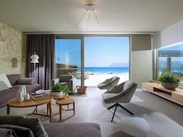 A modern living room with a large sliding glass door leading to a balcony with a view of the sea.