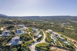 Vista aérea de una zona residencial moderna con varias casas, una carretera sinuosa y una montaña distante.