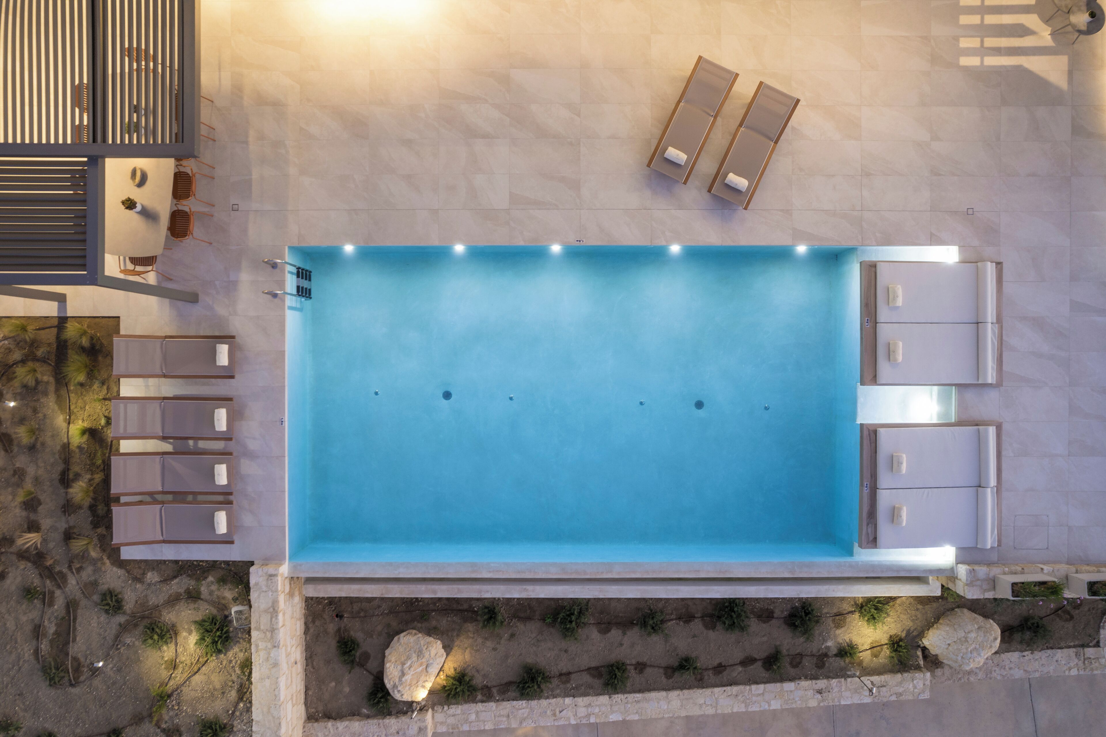 An aerial view of a swimming pool with lounge chairs and a sunbed area.