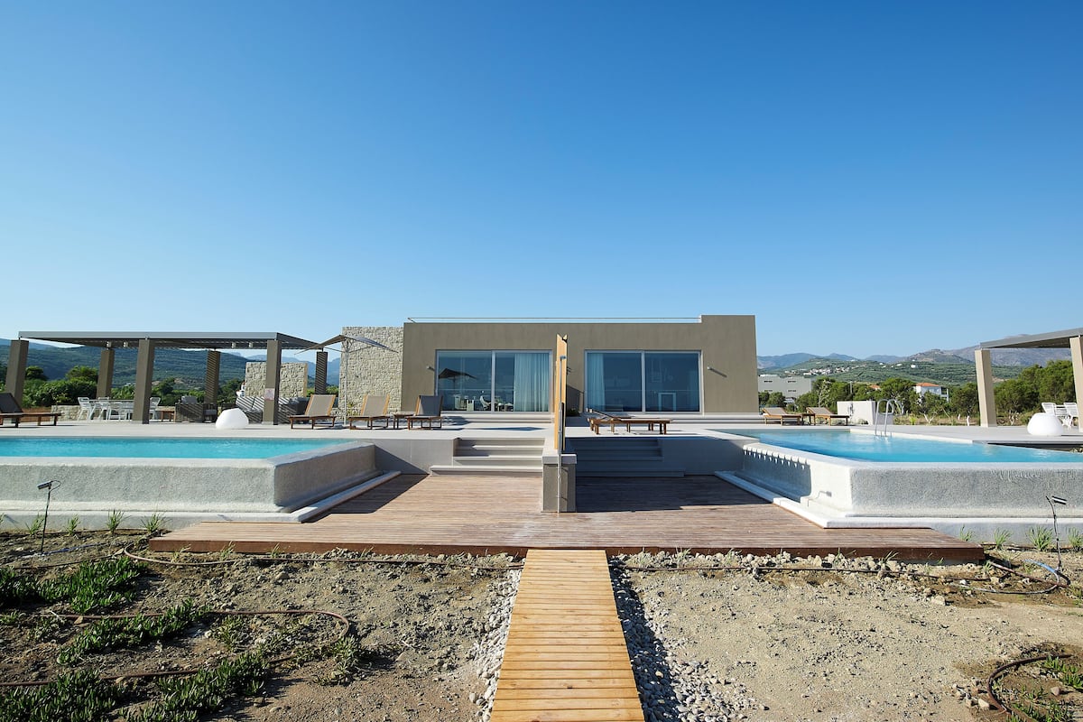 A modern pool area with lounge chairs and a view of the mountains.