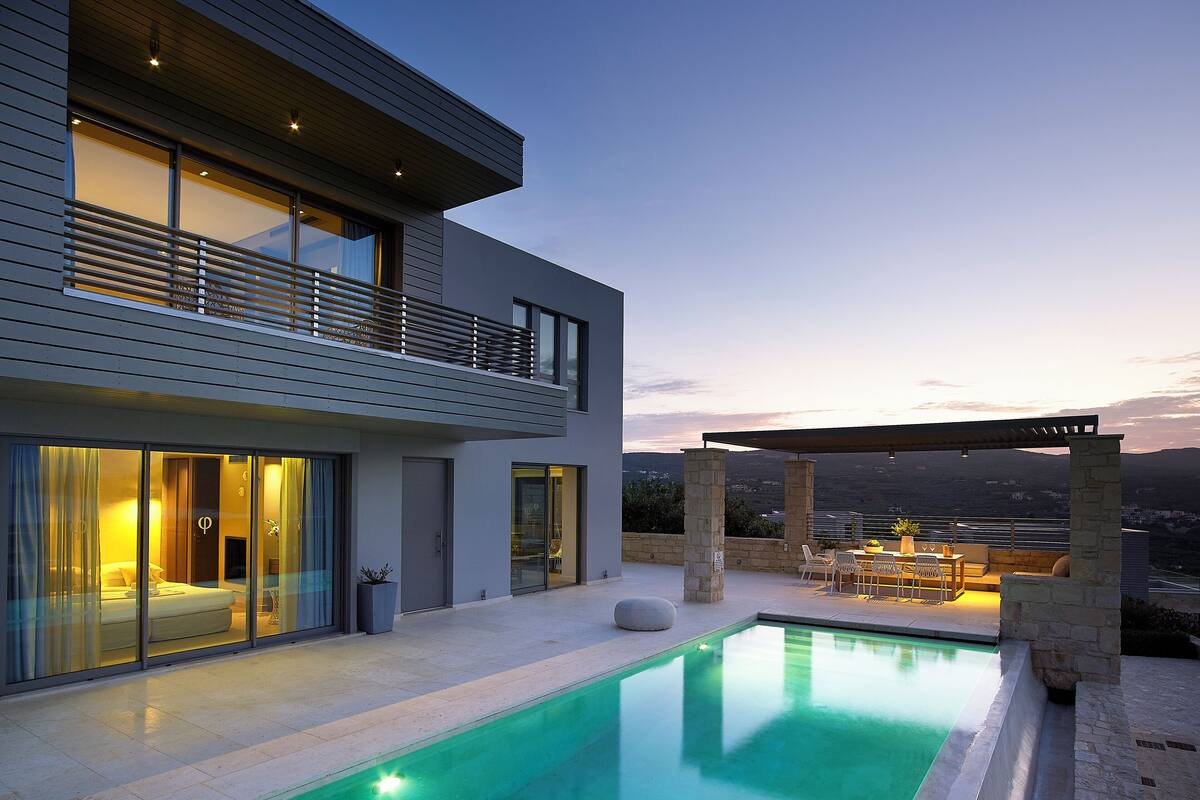 A modern two-story house with a swimming pool, large windows, and a patio area.