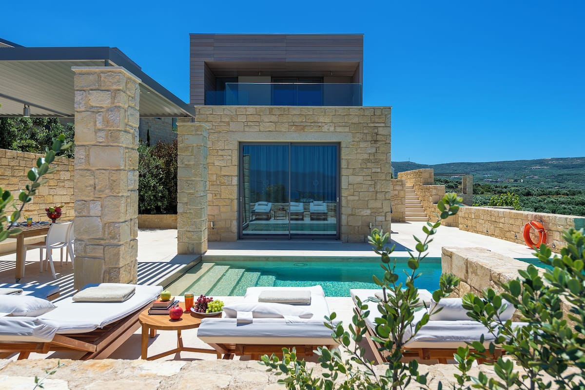 A modern villa with a swimming pool, outdoor seating, and a scenic view.
