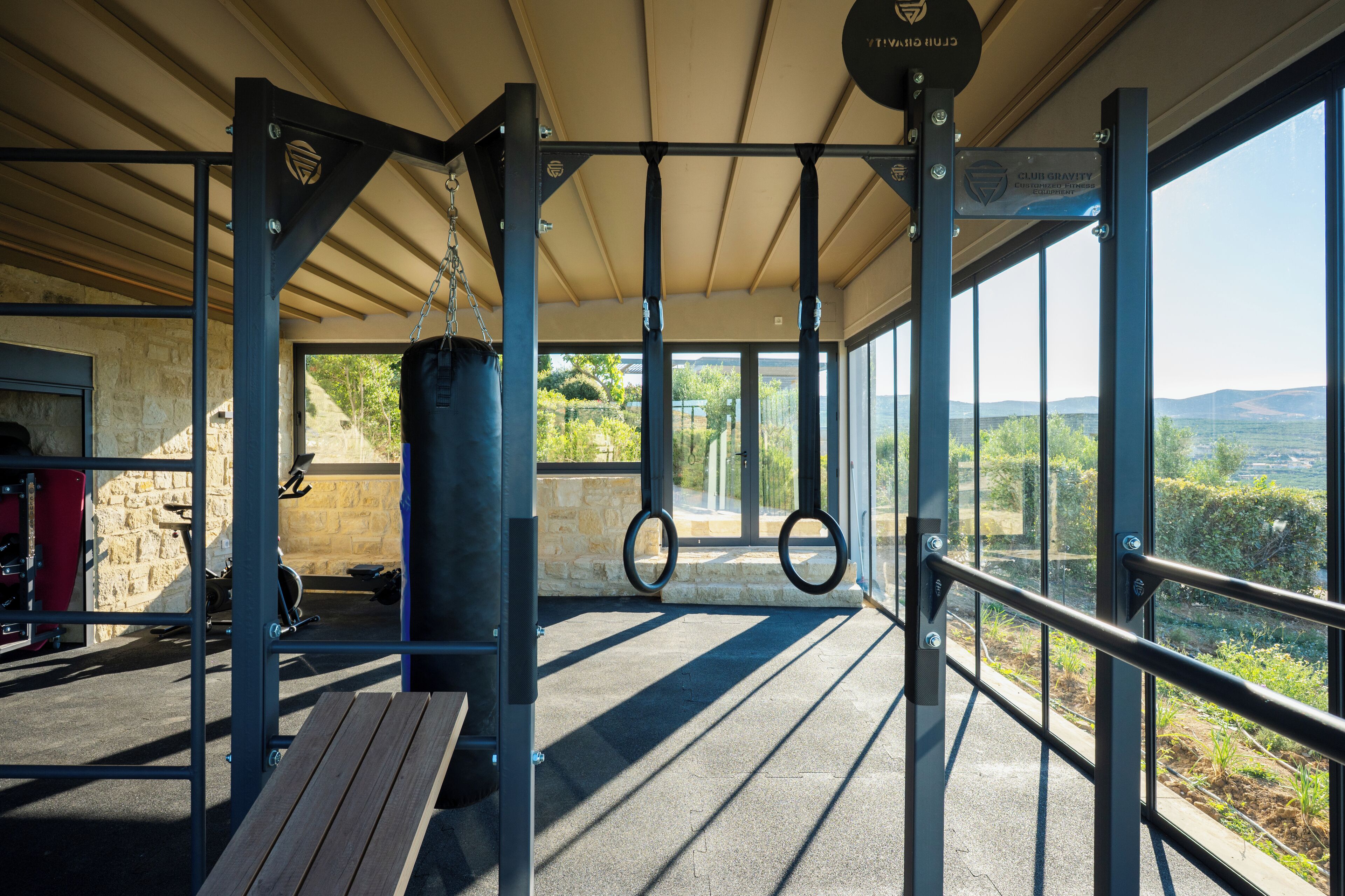 An outdoor gym with exercise equipment, a bench, and a view of the landscape.