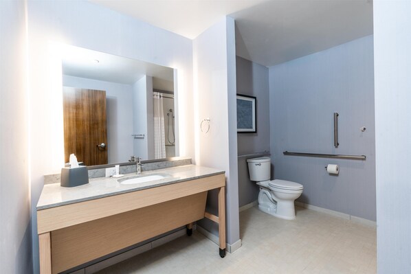 Un baño moderno con un espejo grande, un lavamanos y un inodoro.