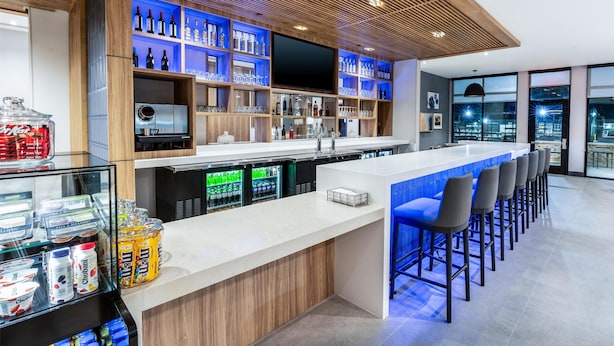 A modern bar area with a long counter, bar stools, and a variety of beverages and snacks. - Hyatt Place Eagle Pass (Eagle Pass)