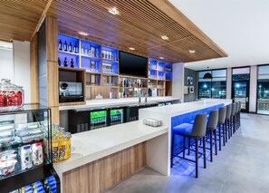 A modern bar area with a long counter, bar stools, and a variety of beverages and snacks. - Hyatt Place Eagle Pass (Eagle Pass)
