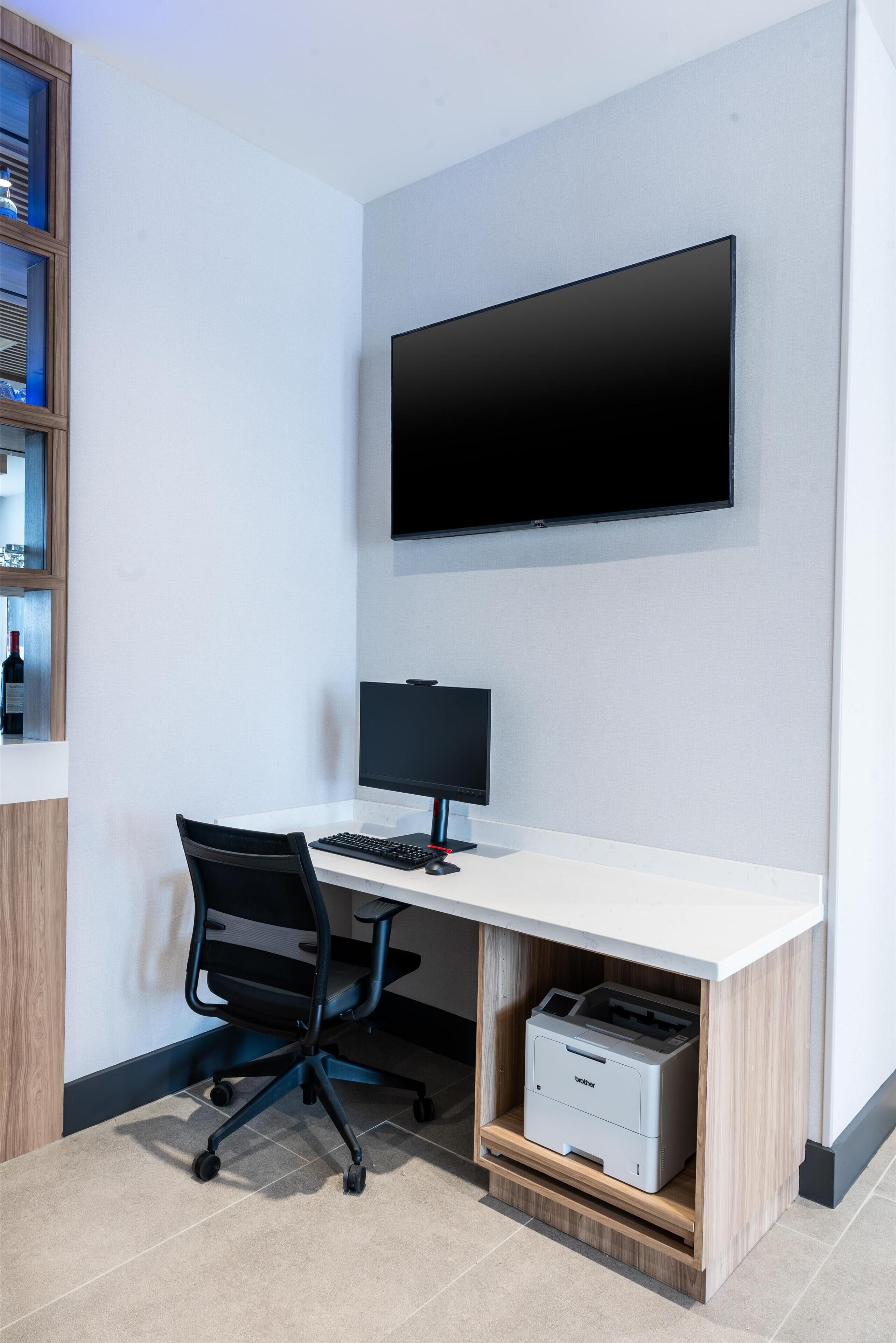 A modern office space with a desk, chair, computer, and printer.