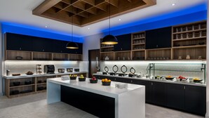 A modern kitchen with a central island, wooden shelves, and a glass display case. - Hyatt Place Eagle Pass (Eagle Pass)
