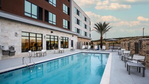 A modern building with a swimming pool, outdoor seating, and a palm tree. - Hyatt Place Eagle Pass (Eagle Pass)
