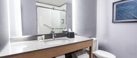 A modern bathroom with a large mirror, a sink, a toilet, and a towel rack.