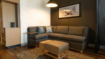 A modern living room with a sectional sofa, a small side table, a bench, and a hanging light fixture.