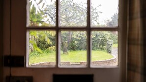 Ein Fenster mit Blick auf eine Wiese und Bäume.