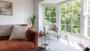 A room with a large window, a sofa, a chair, and a small table with items on it. - Cosy 1BD in Malvern With Stunning Views (Malvern)