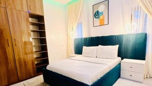Une chambre à coucher avec un lit, des tables de chevet, une armoire et un tableau au mur.
