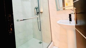 Une salle de bain moderne avec une douche à parois de verre, un lavabo blanc et un miroir avec un éclairage au-dessus.