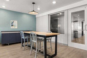 A modern kitchen with a wooden table and chairs, a blue accent wall, and a glass door leading to another room.